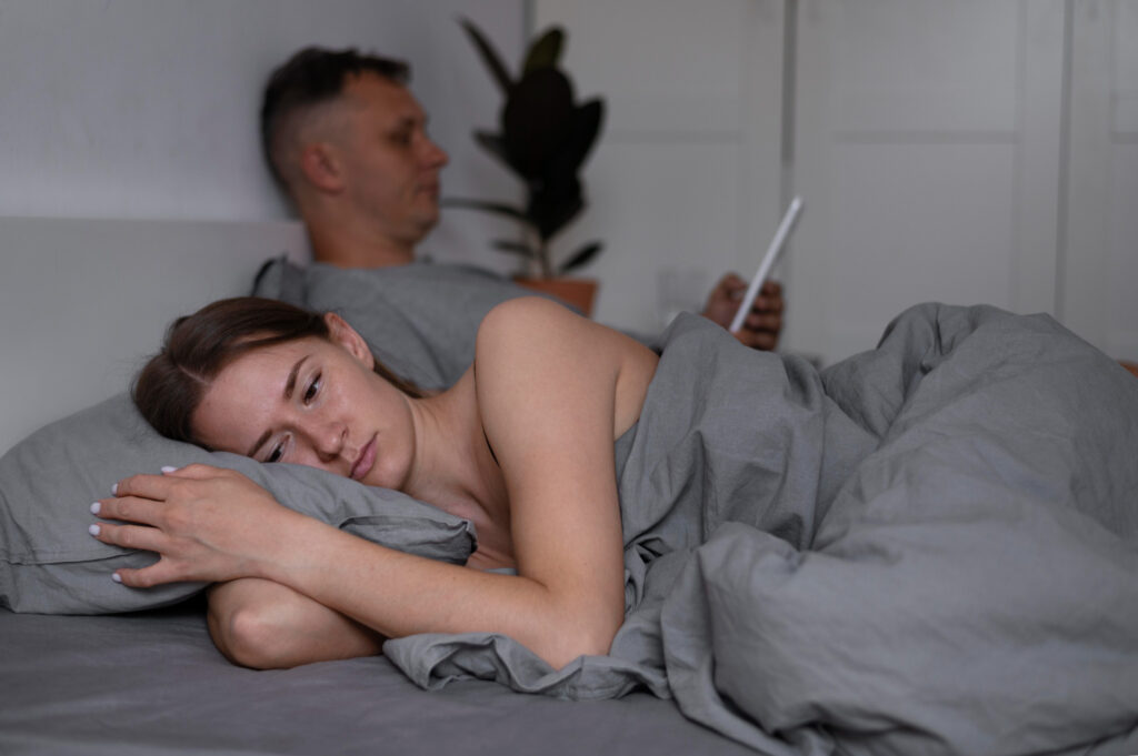 Couple looking tired and frustrated in bed from poor sleep.